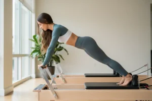  Femme brune en tenue de sport legging gris sur un pilates reformer 
