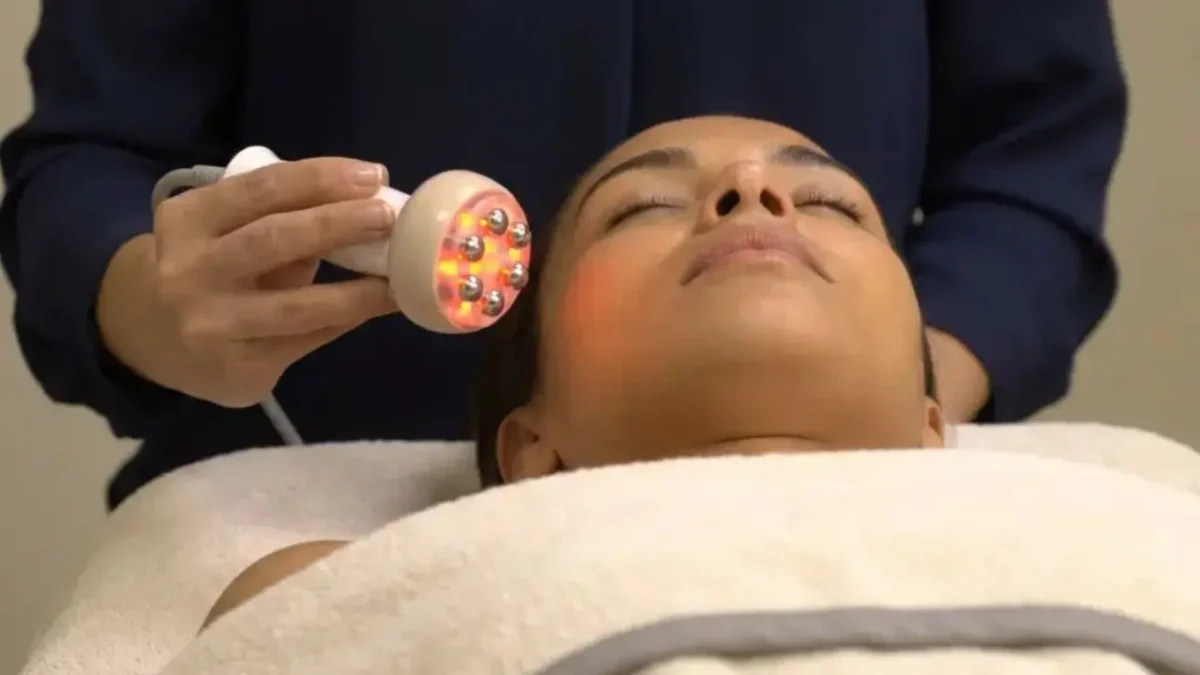Femme allongé recouverte d'une serviette écru et recevant un soin de radiofréquence par une professionnelle.