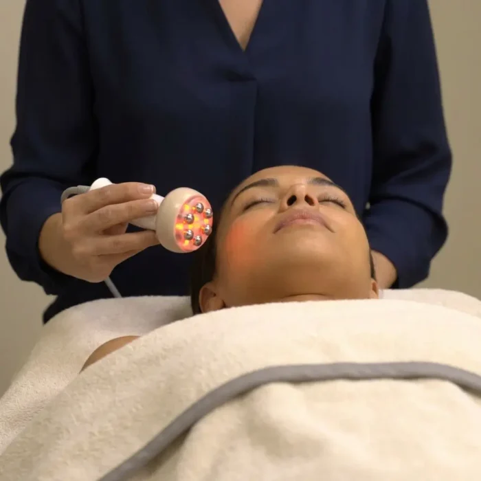 Femme allongé recouverte d'une serviette écru et recevant un soin de radiofréquence par une professionnelle.