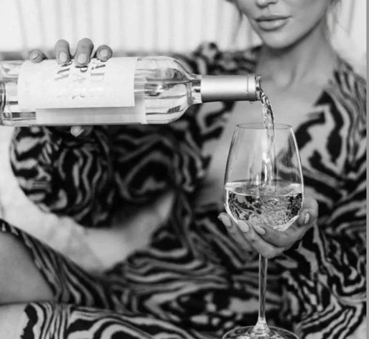 femme habillée d'une robe à motif tigré et se servant un verre de vin